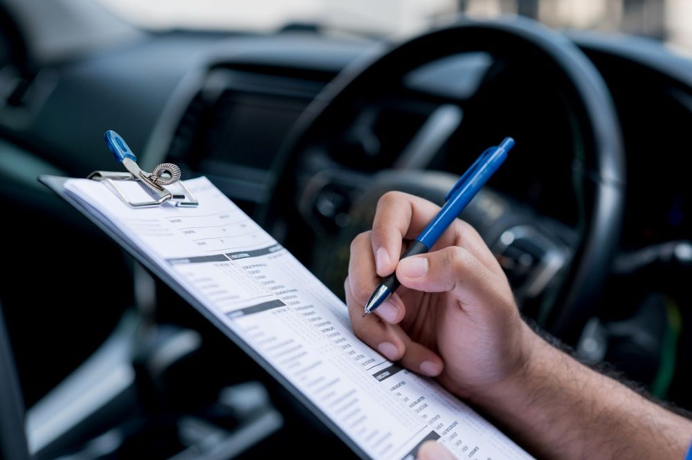 A Man Is Signing A Document With A Pen — East Lismore Automotive in East Lismore, NSW
