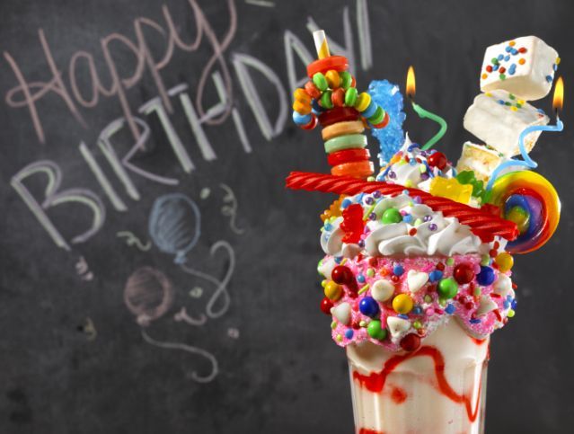 A birthday milkshake in front of a chalkboard that says happy birthday