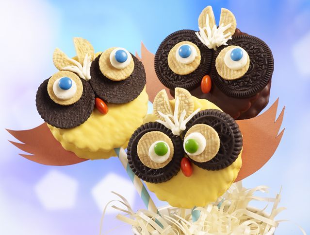 Three cupcakes decorated to look like owls on a stick