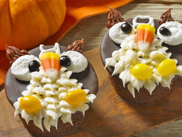 Two cupcakes decorated to look like owls with candy corn on them