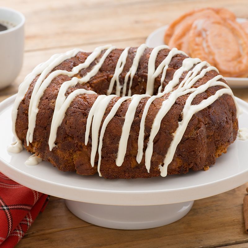 A bundt cake with white frosting on a white plate