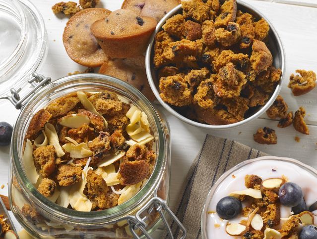 A jar of granola and a bowl of yogurt are on a table.