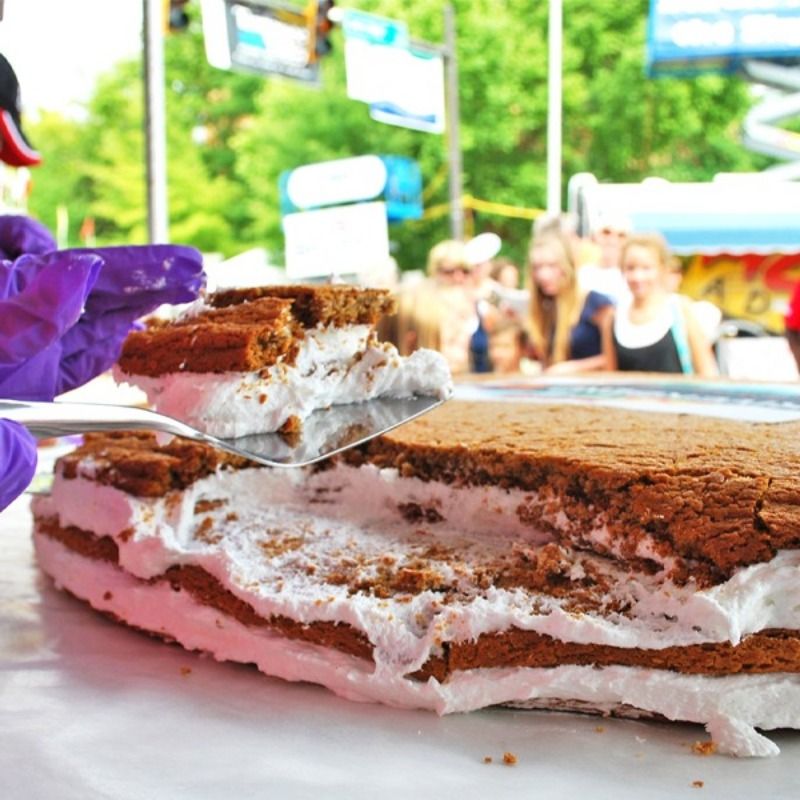 A person wearing purple gloves is taking a slice of cake