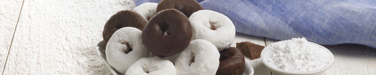 A bunch of chocolate covered donuts are sitting on a table.