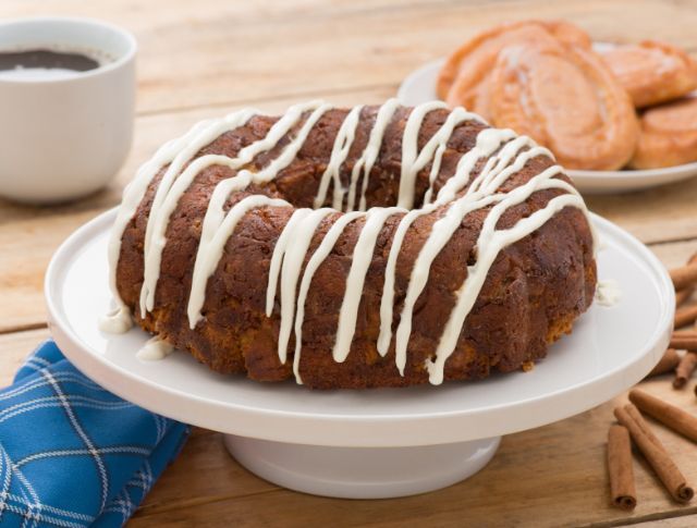A bundt cake with white frosting is on a white plate.