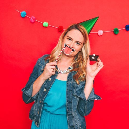 A woman is wearing a party hat and holding a cake.