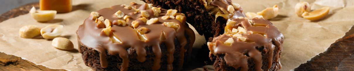 A close up of a chocolate cupcake with nuts on top on a table.