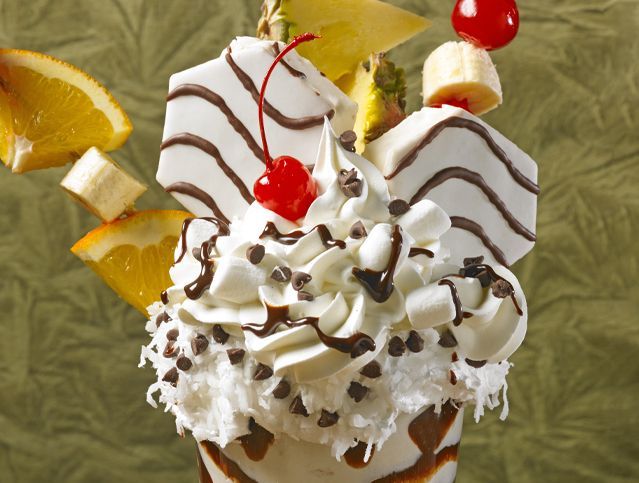 A milkshake with whipped cream chocolate chips and fruit on top