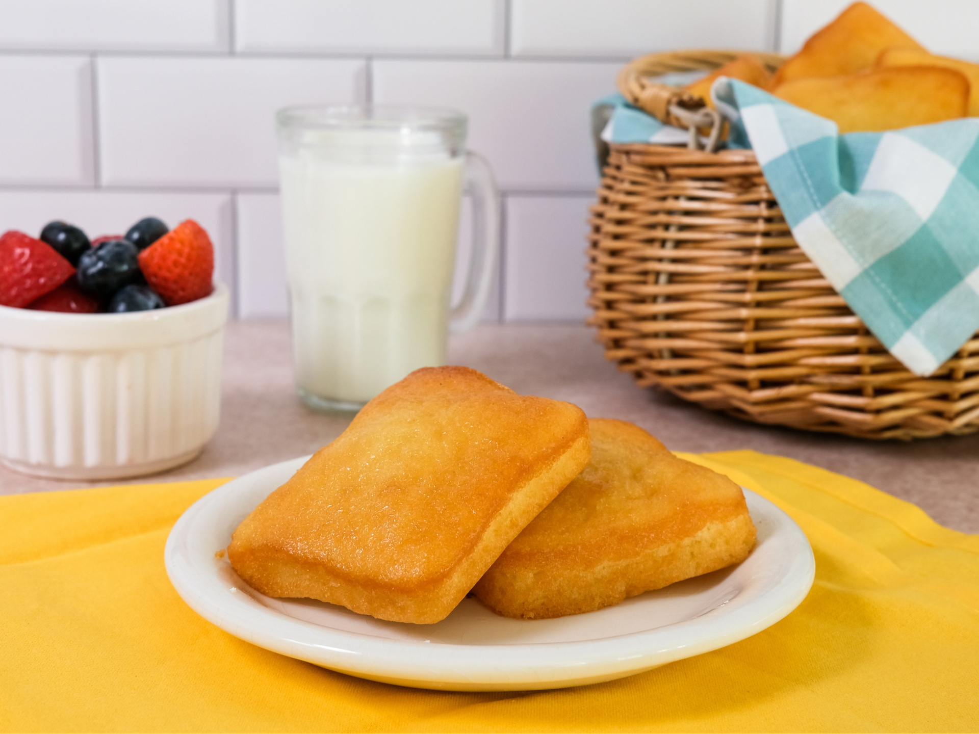 two pound cakes on a white plate with glass, a basket and fresh fruit in the background 