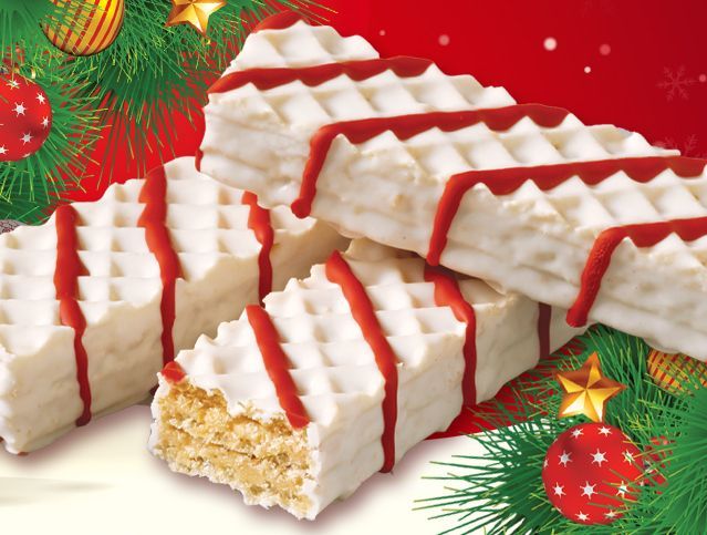 A stack of white wafers with red stripes and christmas decorations in the background