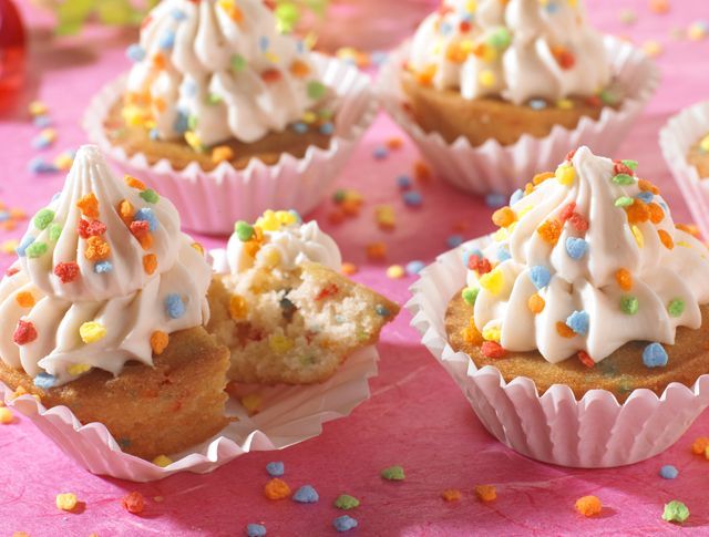Cupcakes with frosting and sprinkles on a pink table