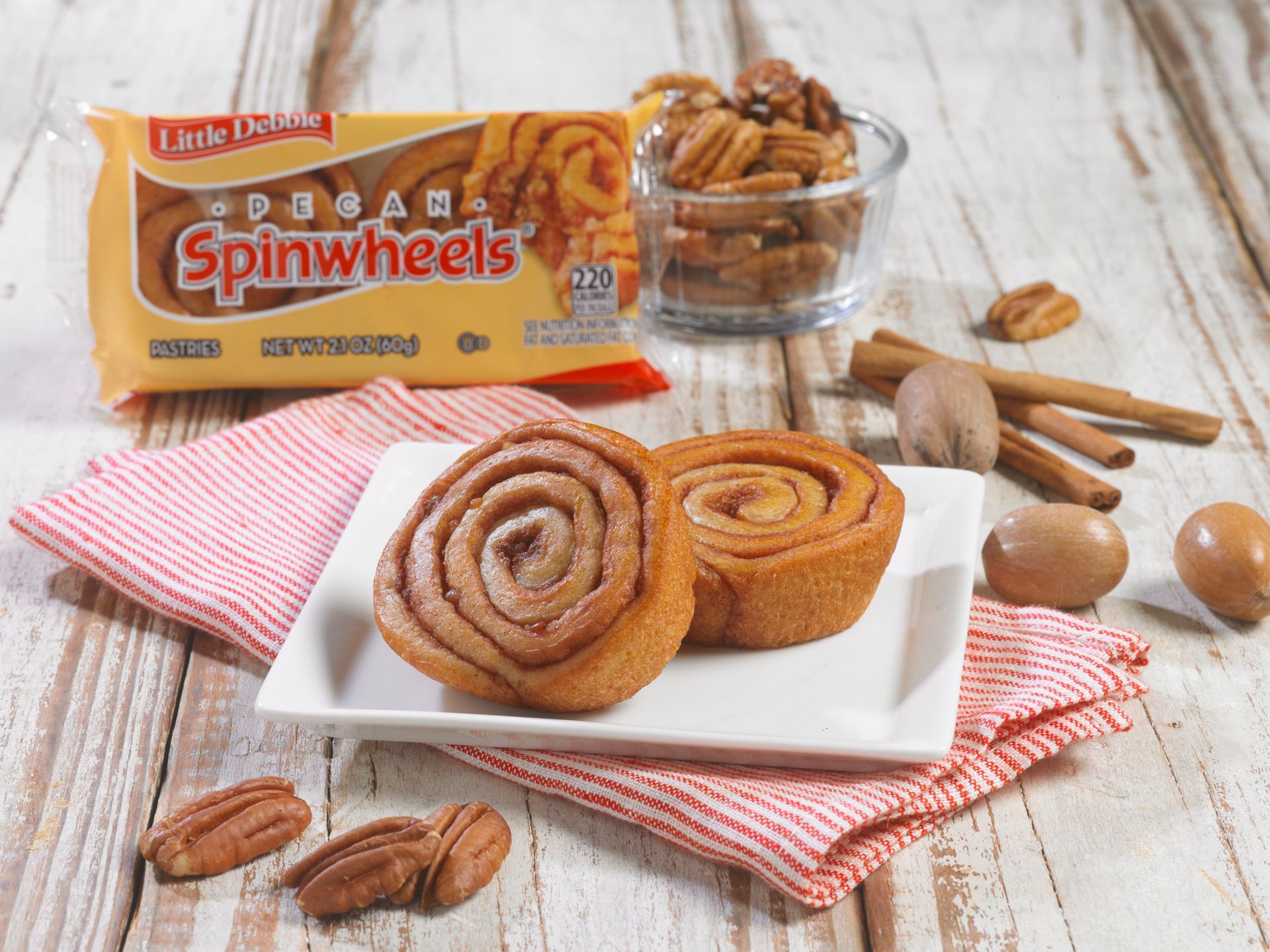 Two pecan spinwheels on a white plate next to a bag of spinwheels