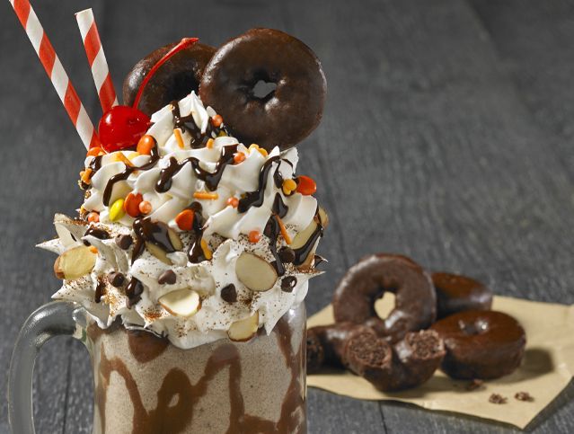 A milkshake with chocolate donuts and whipped cream on top
