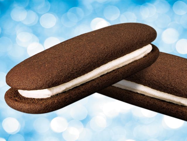 Two chocolate sandwich cookies with white frosting on a blue background