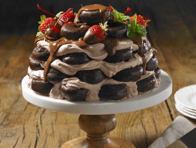 A chocolate cake with strawberries on top is on a cake stand