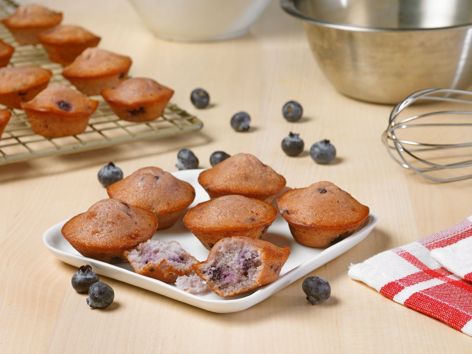 A white plate topped with muffins and blueberries on a table