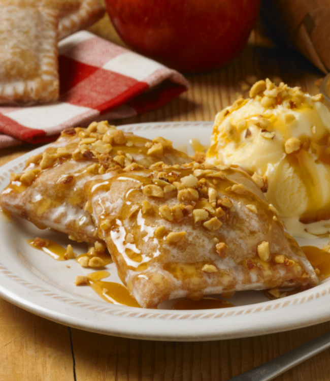 apple pies topped with nuts, caramel sauce and ice cream