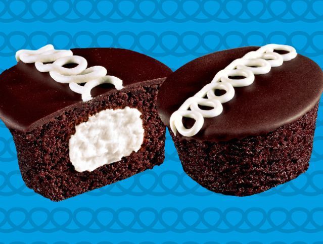 Two chocolate cupcakes with white frosting on a blue background