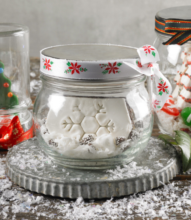 glass jars decorated as snow globes with little debbie christmas treats