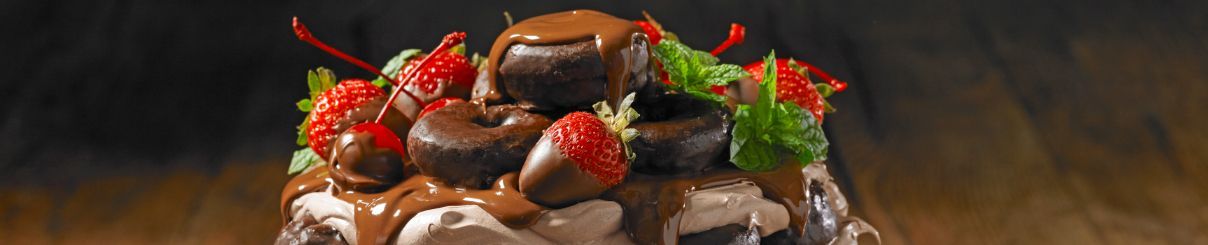 A chocolate cake with strawberries and chocolate covered cherries on top.