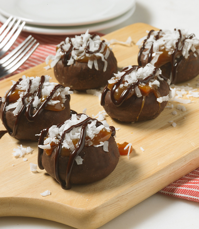 frosted mini donuts topped with caramel, chocolate drizzle and coconut flakes