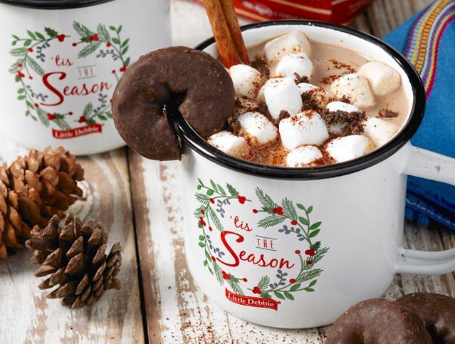 A cup of hot chocolate with marshmallows and a donut in it