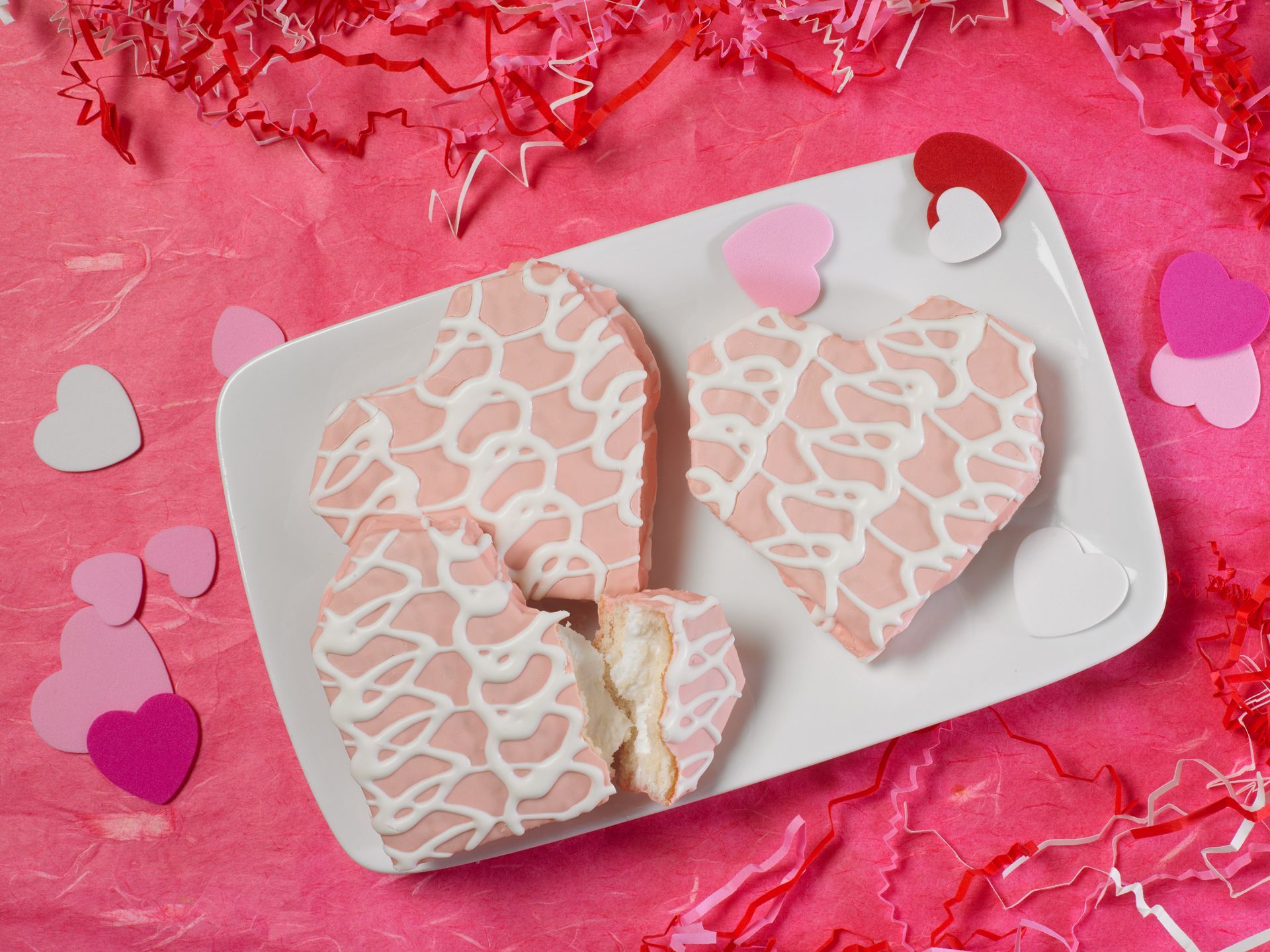 three big pack valentine cakes on a white plate with hot pink background
