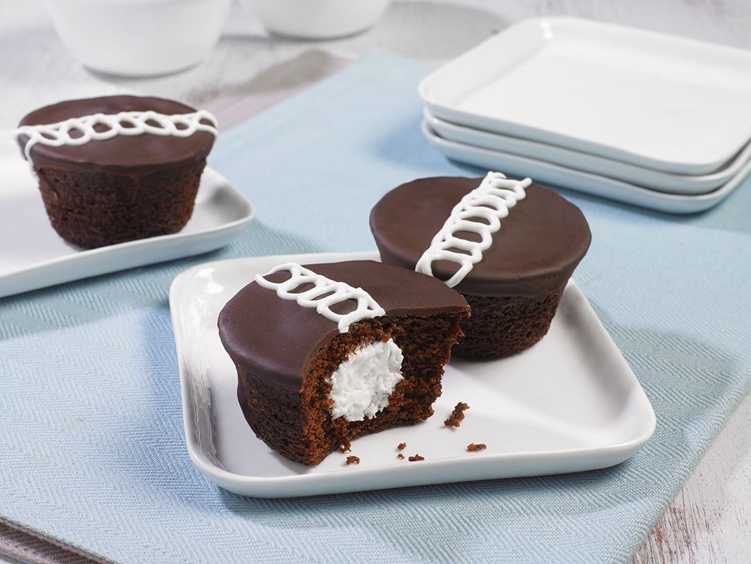 Two chocolate cupcakes on a white plate with a bite taken out of one of them