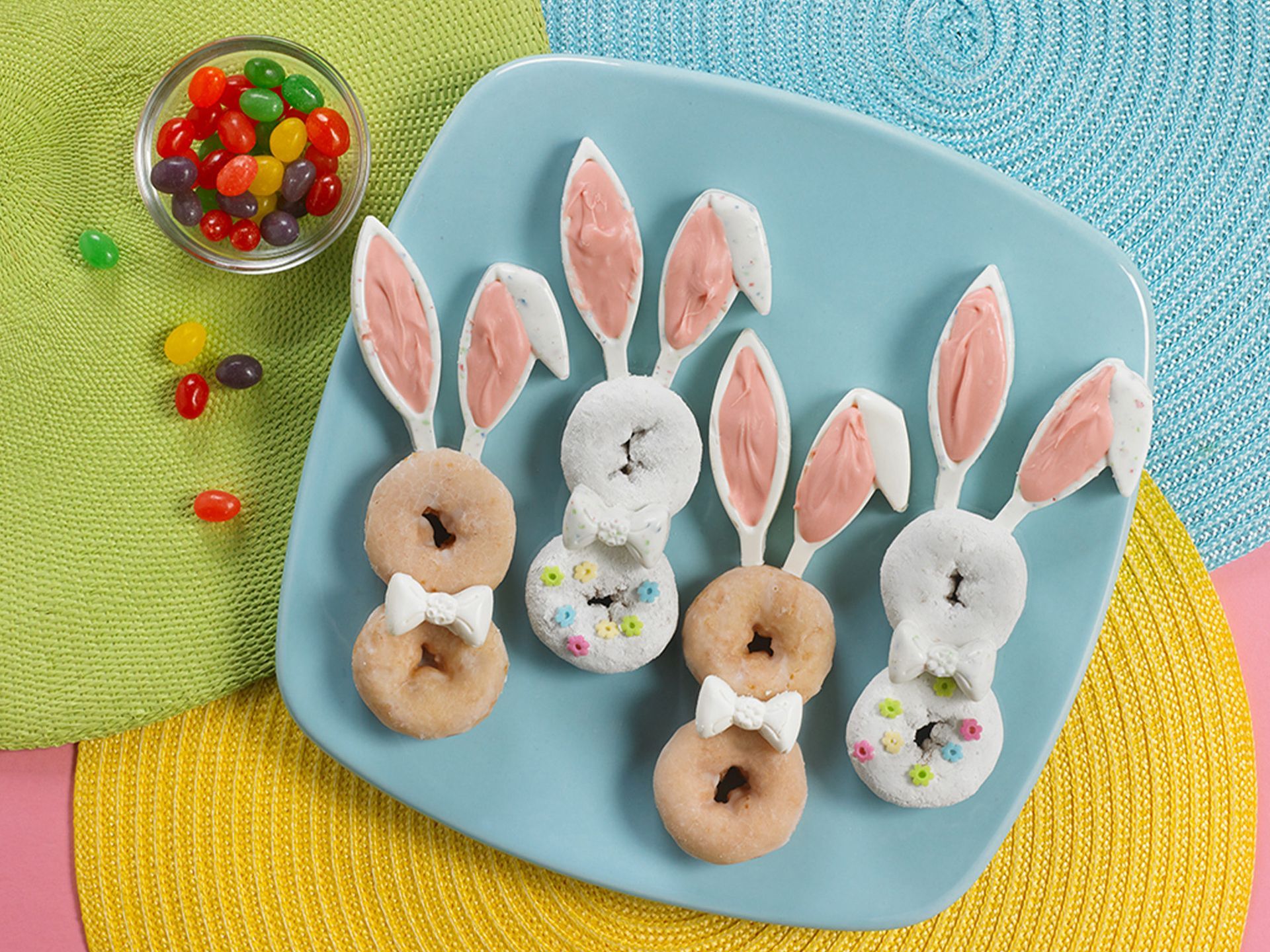 glazed and powdered mini donuts decorated as easter bunnies on a blue plate