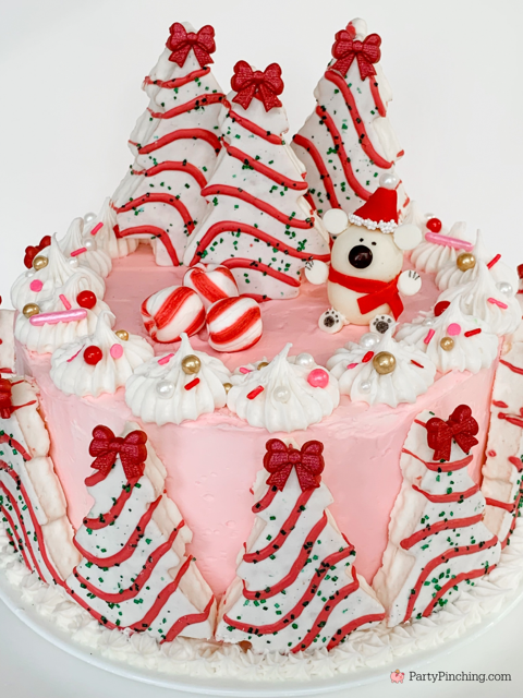 christmas tree cakes decorated around a cake with pink peppermint frosting and a truffle polar bar