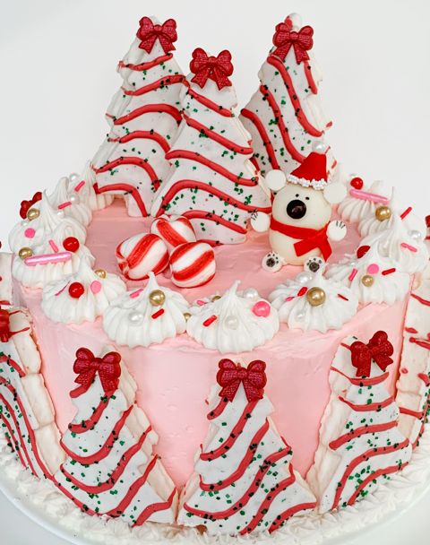 pink frosted cake decorated with polar bears and christmas tree cakes