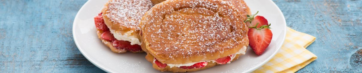 A plate of pancakes with strawberries and powdered sugar on a table.