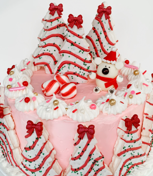 pink frosted cake decorated with polar bears and christmas tree cakes