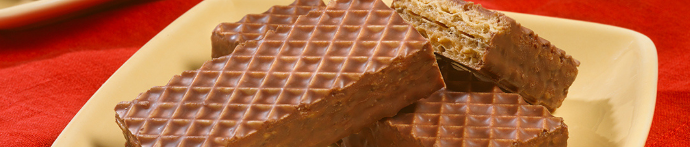 Three chocolate wafers are stacked on top of each other on a plate.