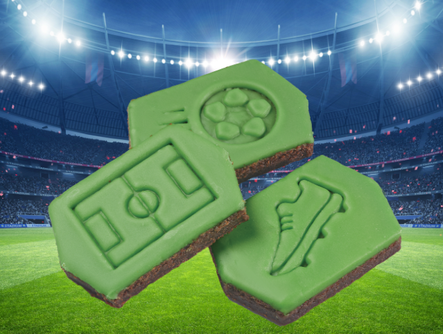 Three brownies with green frosting on them and stamps of a field, shoe and soccer ball