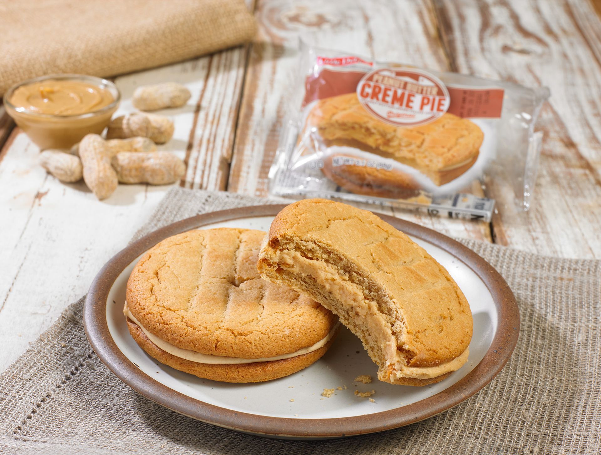 Two peanut butter creme pies on a plate with a bite taken out of one of them