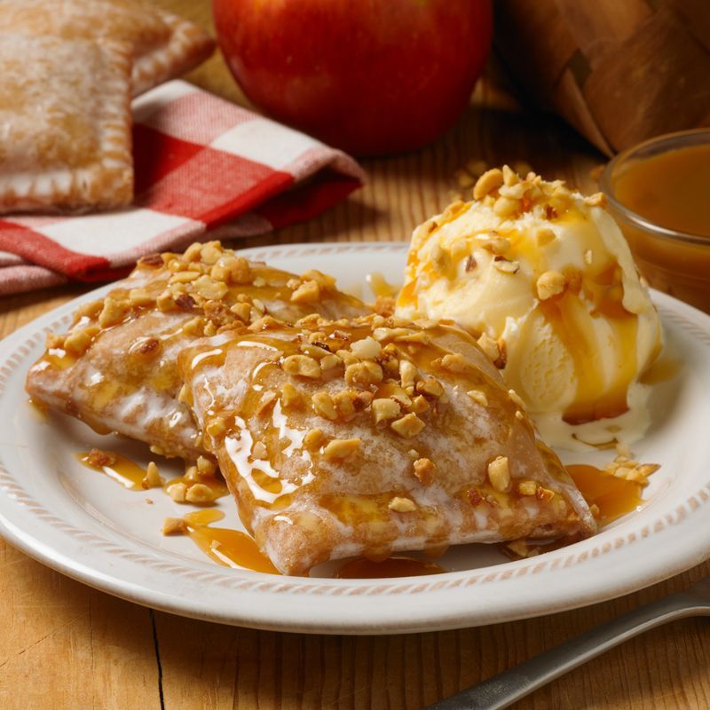 mini apple fruit pies topped with caramel sauce, nuts and vanilla ice cream