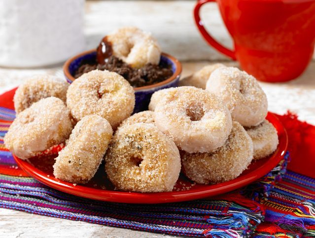 A red plate topped with donuts and a cup of coffee.
