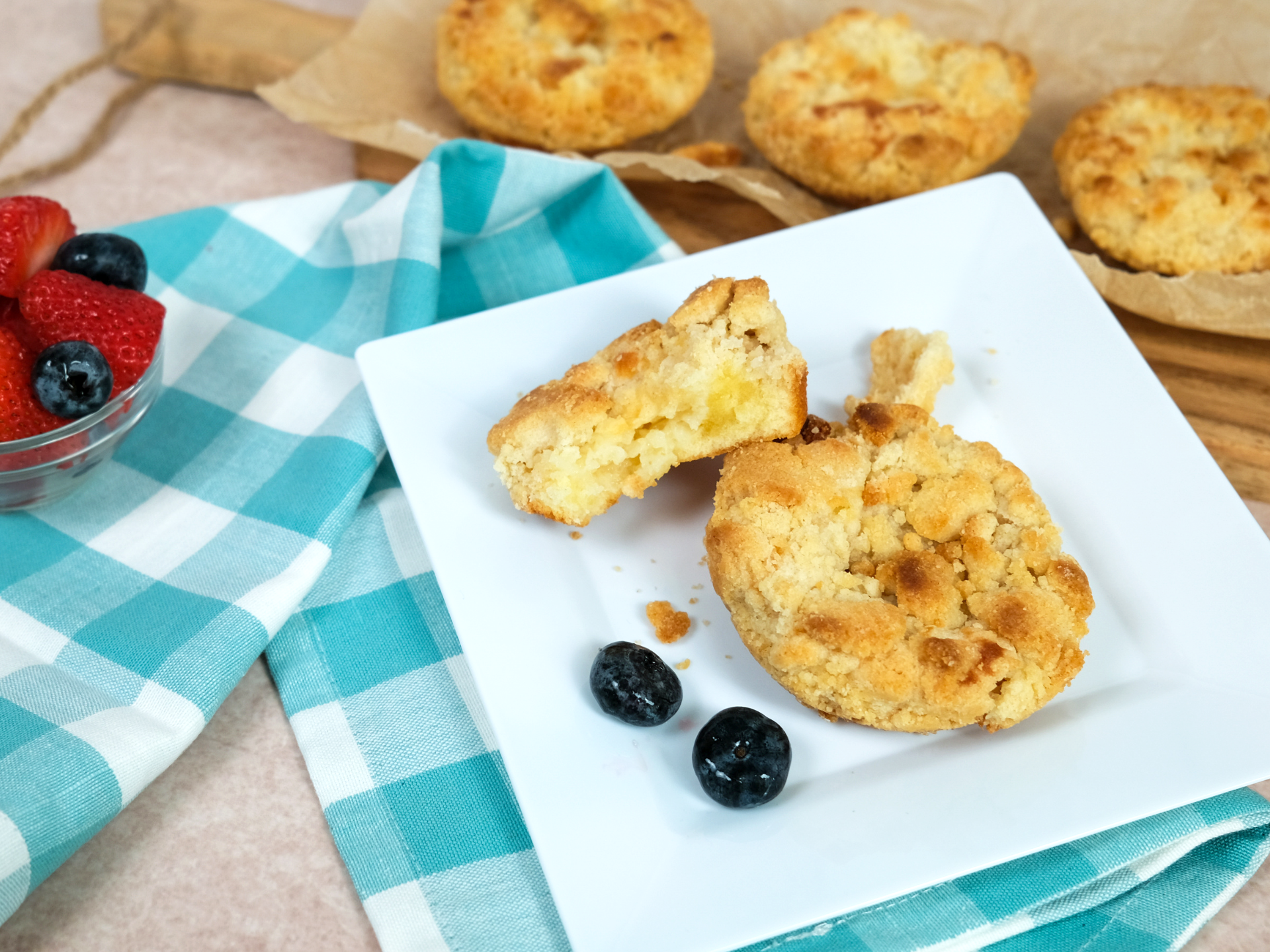 two cream cheese struesel pastries on a white plate with three in the background