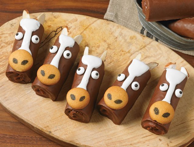 A wooden cutting board topped with chocolate covered horses