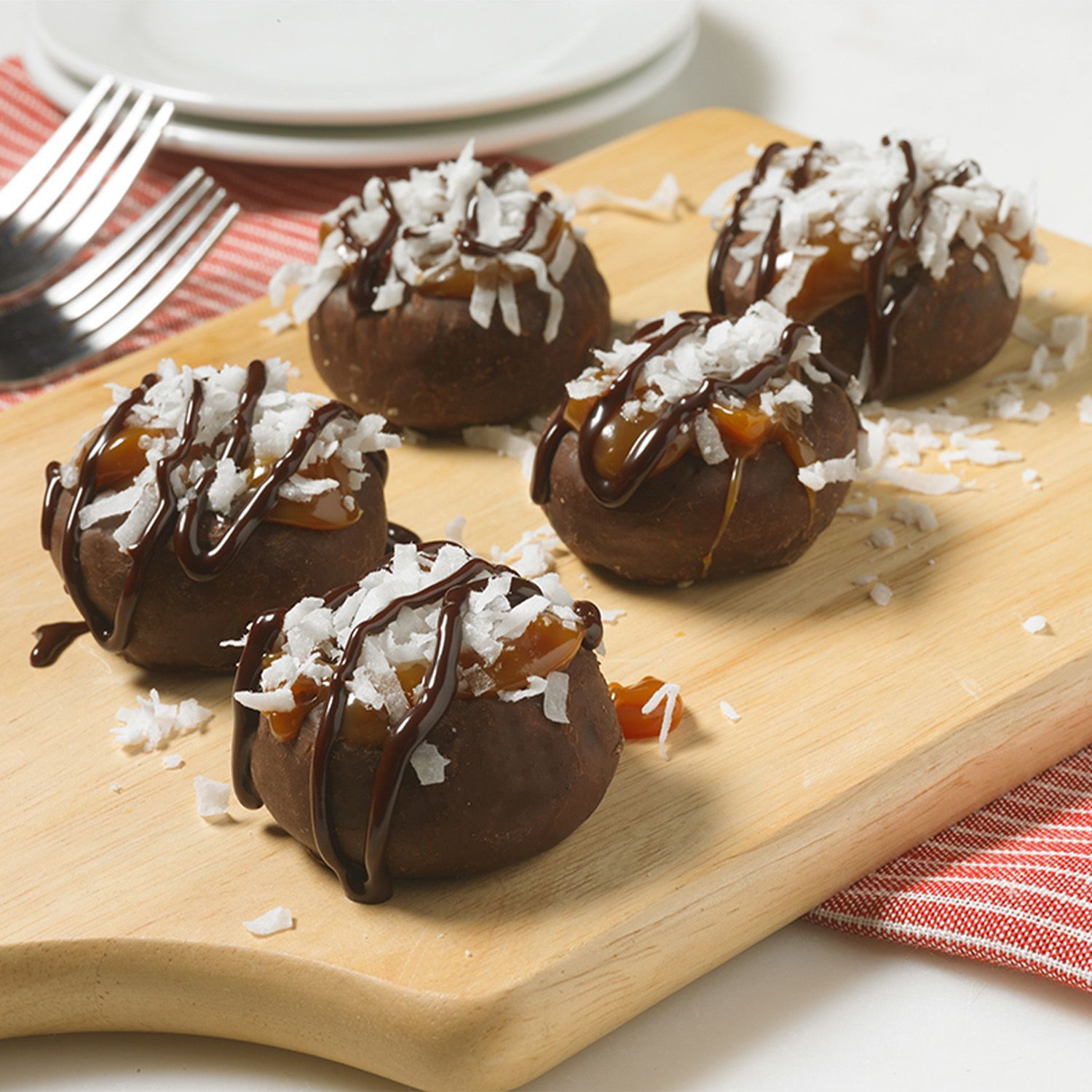 A wooden cutting board topped with chocolates and coconut