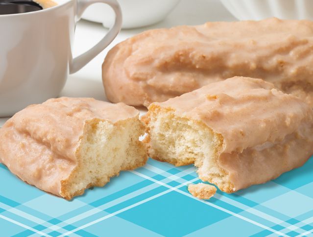 A donut with a bite taken out of it sits on a table next to a cup of coffee