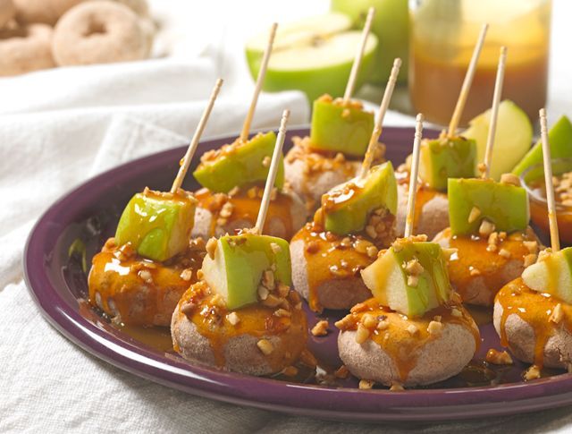 A purple plate topped with caramel apples on sticks