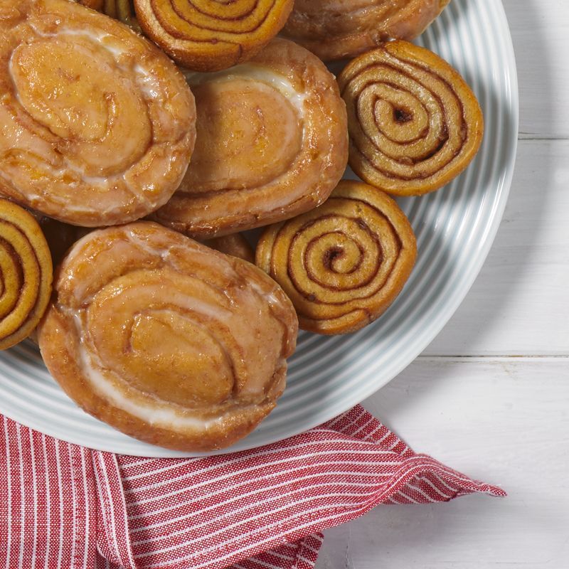 A plate of cinnamon rolls on a table with a red and white striped napkin
