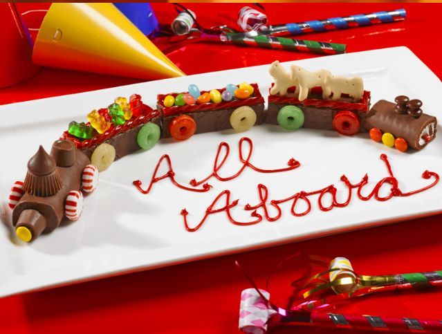 A white plate with a train made out of chocolate and candy that says all aboard