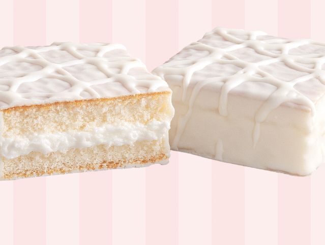 Two pieces of cake with white frosting on a pink striped background.