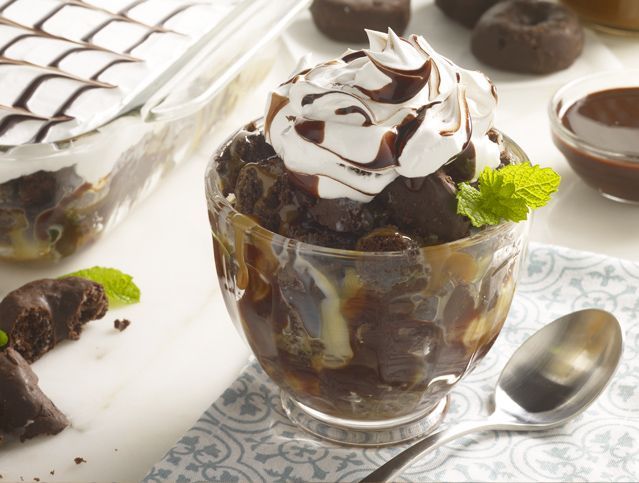 A bowl of chocolate pudding with whipped cream and mint leaves