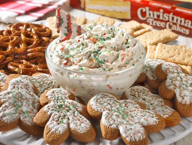 A bowl of dip is surrounded by gingerbread cookies and pretzels.
