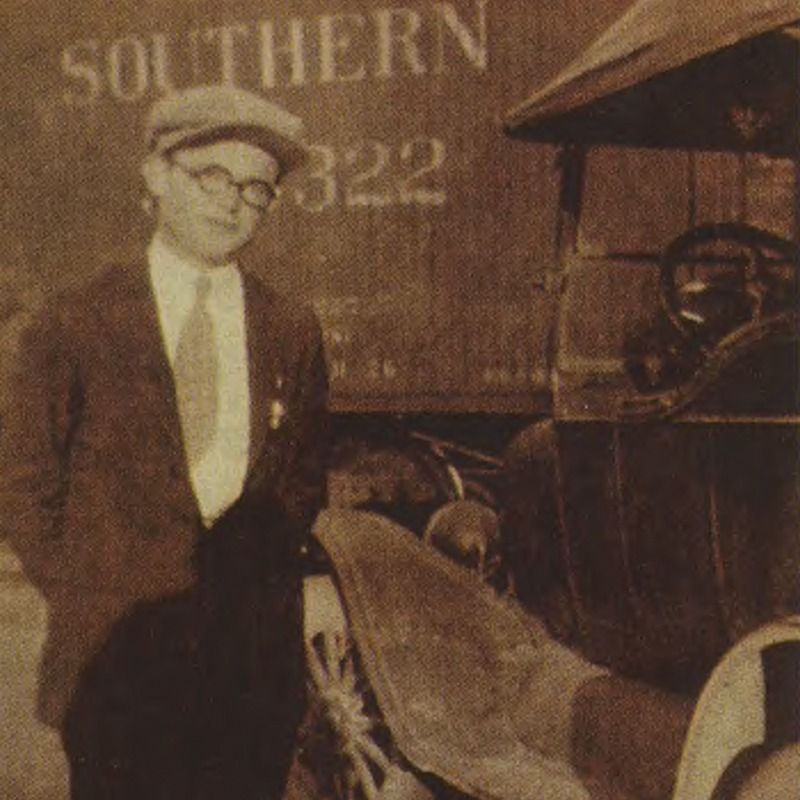 A man in a suit and tie stands in front of a southern truck