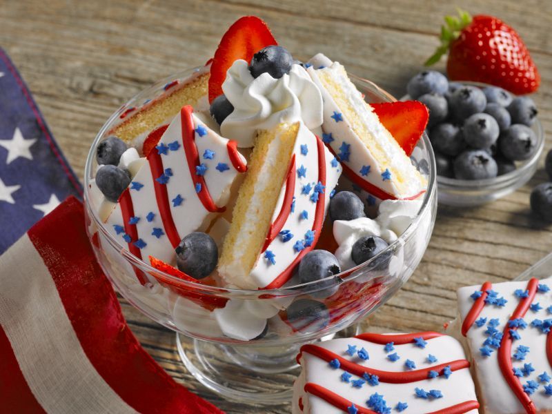 red, white and blue cakes layered with whipped cream and berries in a bowl